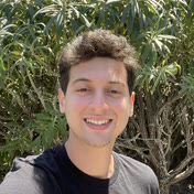 A photo of me smiling with some green leafy trees in the background
